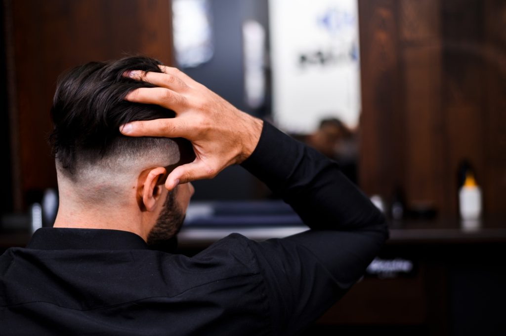A man looking at his reflection after his haircut at a Barber Shop in Stafford.