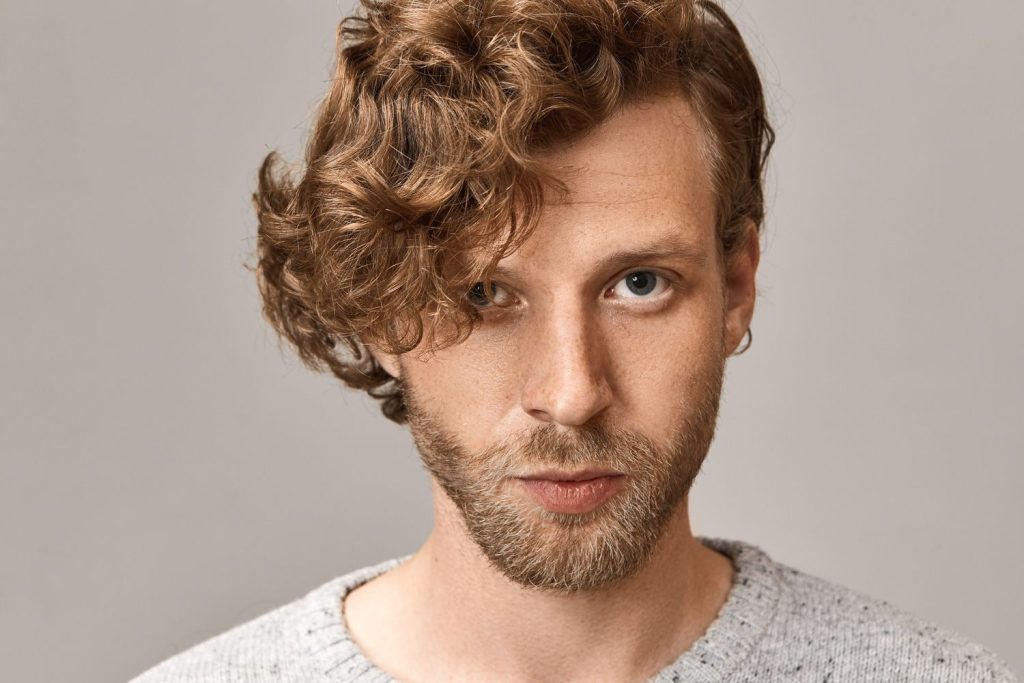 A headshot of a man in his mens haircuts near The Fountains stylish cut.