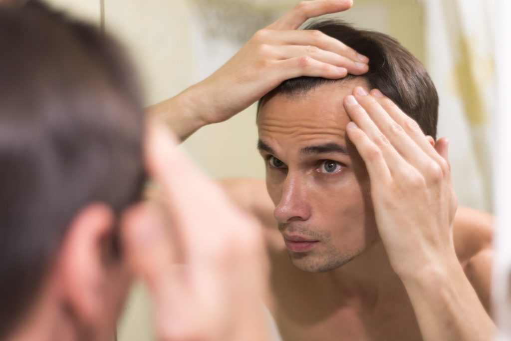 A man looking at the mirror wearing his Mens hair replacement system in Southmeadow hairline fix