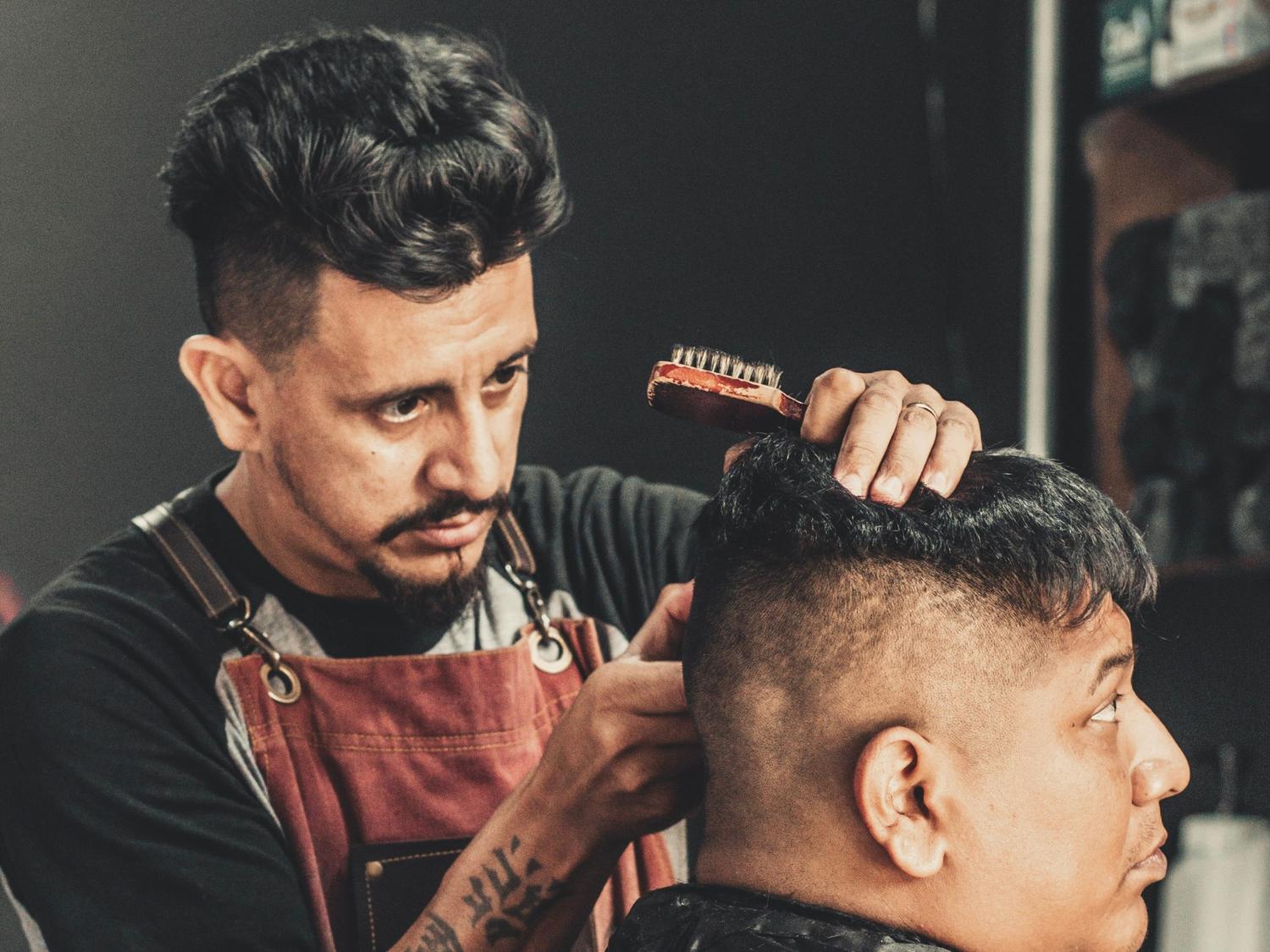 Expert barber at barber shop Stafford giving a sharp haircut in a modern, inviting barbershop atmosphere.
