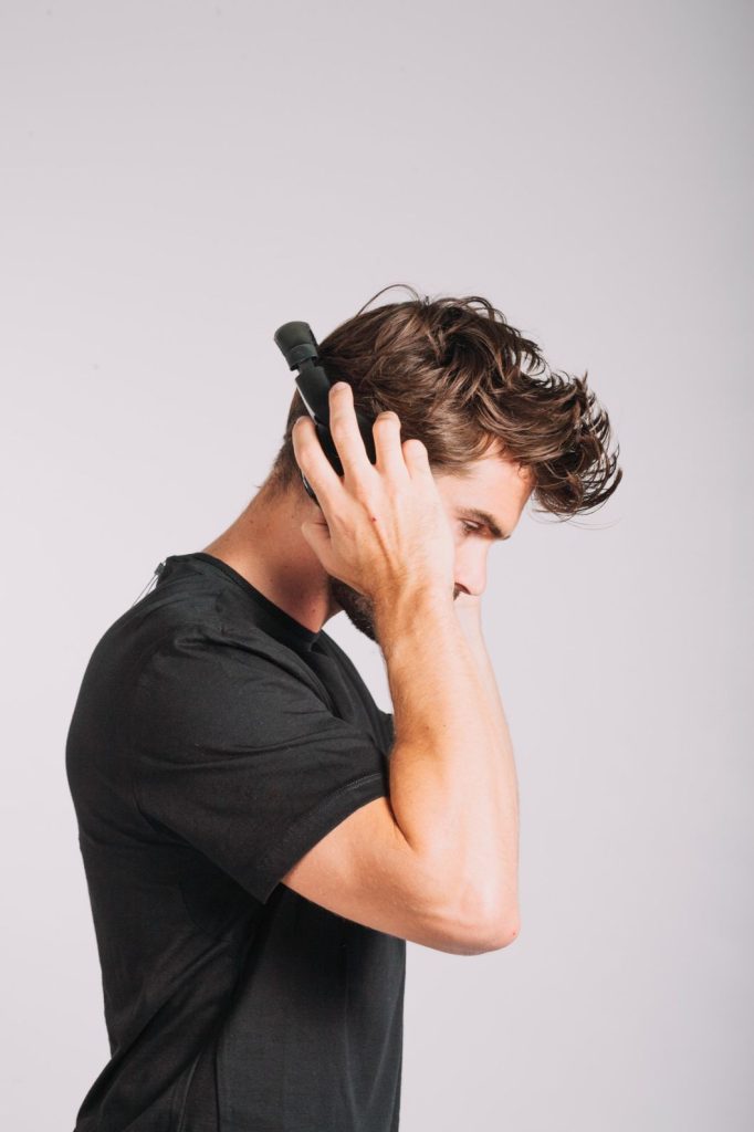 Man thoughtfully adjusting a discreet men's toupee, featuring natural hair restoration options in Stafford