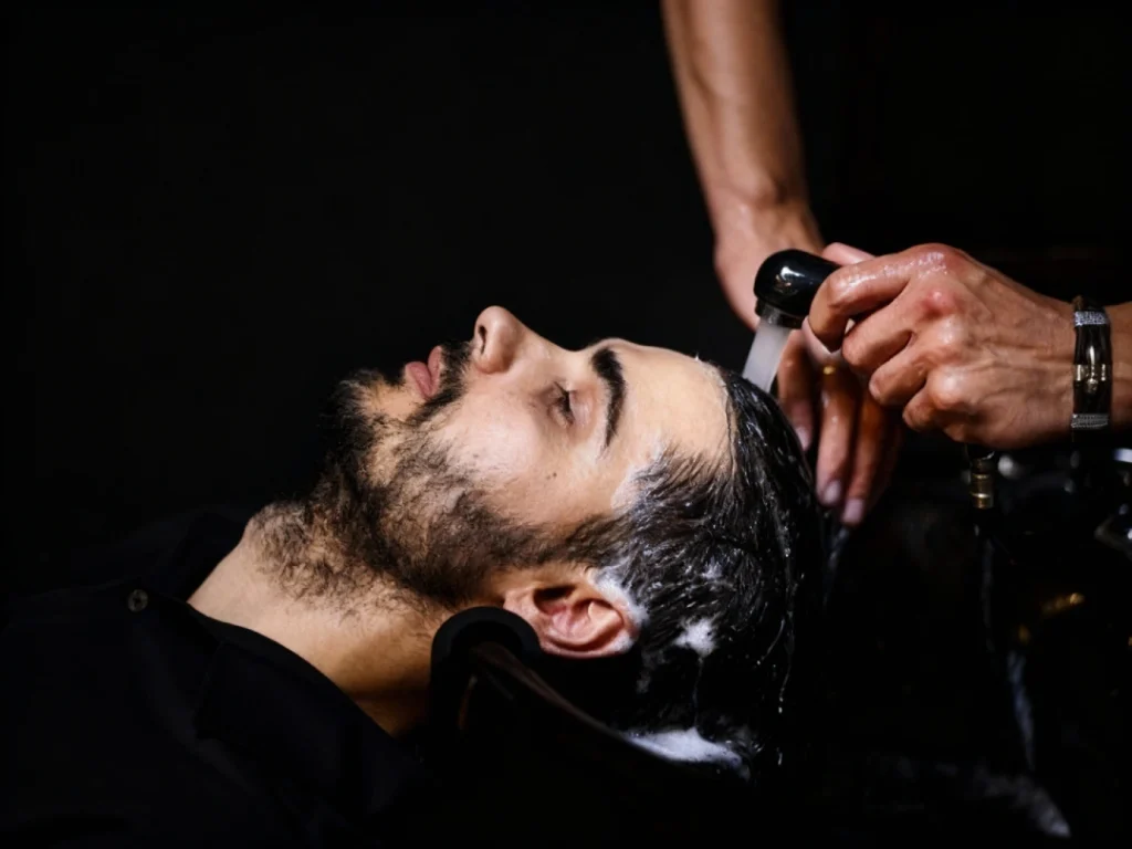 Man receiving professional men's toupee maintenance in Stafford, relaxing as stylist adjusts hair with care.