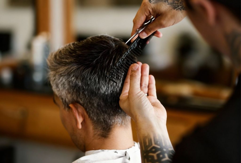Expert barber perfecting a classic taper on mature mens haircuts with gray hair