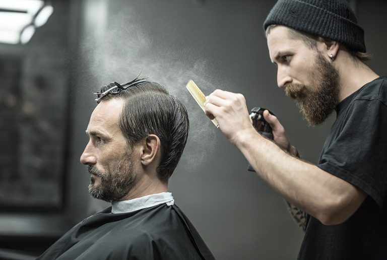 Best barber shop experience with a stylist spraying product for a classic men's hairstyle finish.